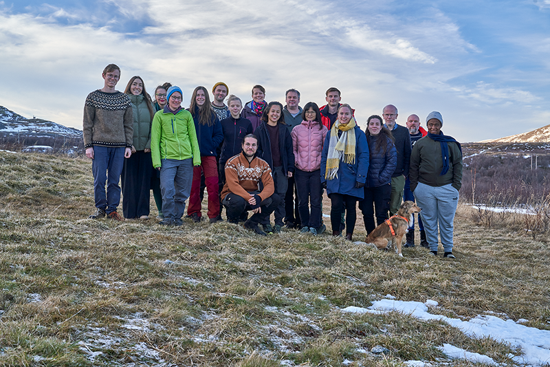 The image shows a group of participants posing for a group photo in the countryside.