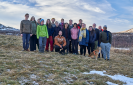 The photo shows a group of participants posing for a group photo in the countryside